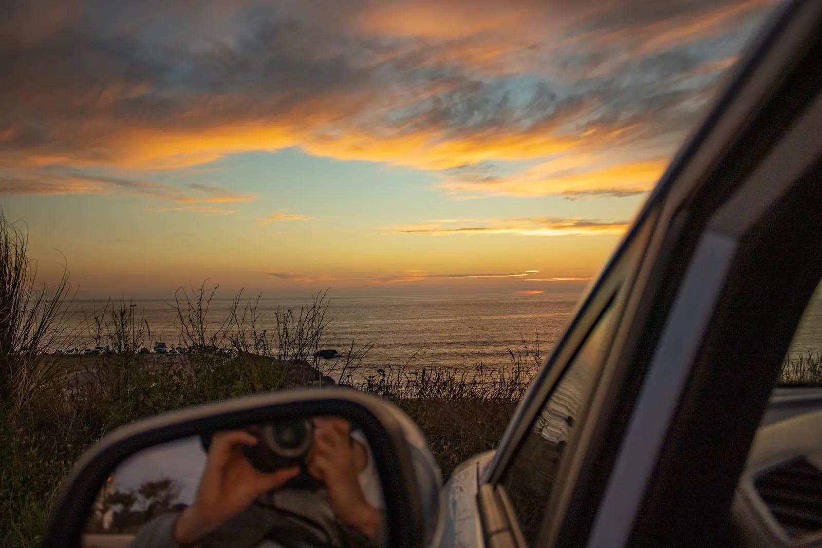 Tramonto sulla costa atlantica visto dallo specchietto laterale di un'auto a noleggio